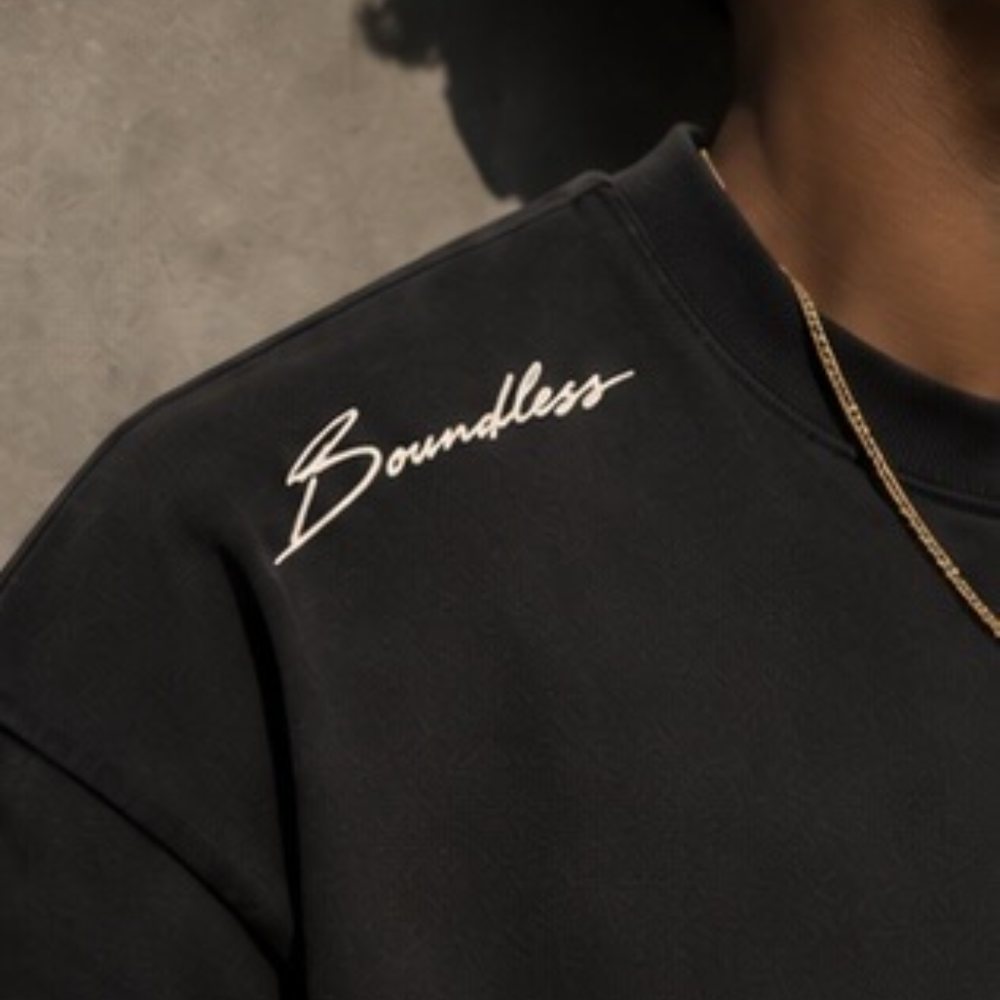 Close-up of a black T-shirt shoulder with Boundless in cream script